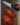 Sliced tomatoes on a wooden cutting board with a knife and a hand holding it.