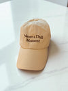 Cream Canvas Baseball hat with brown thread 'never a dull moment' on a countertop