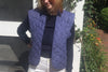 Navy Kitchen Vest, Gilet Inspired, In photo is a girl in white shorts, a navy sweater, oval sunglases smiling near a door with plants in the back.