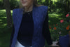 Lightweight Navy Vest for Kitchen use, water repellent, navy closure. Pictured in a lawn grass beautiful and a girl standing in white pants, a navy sweater and a simple necklace