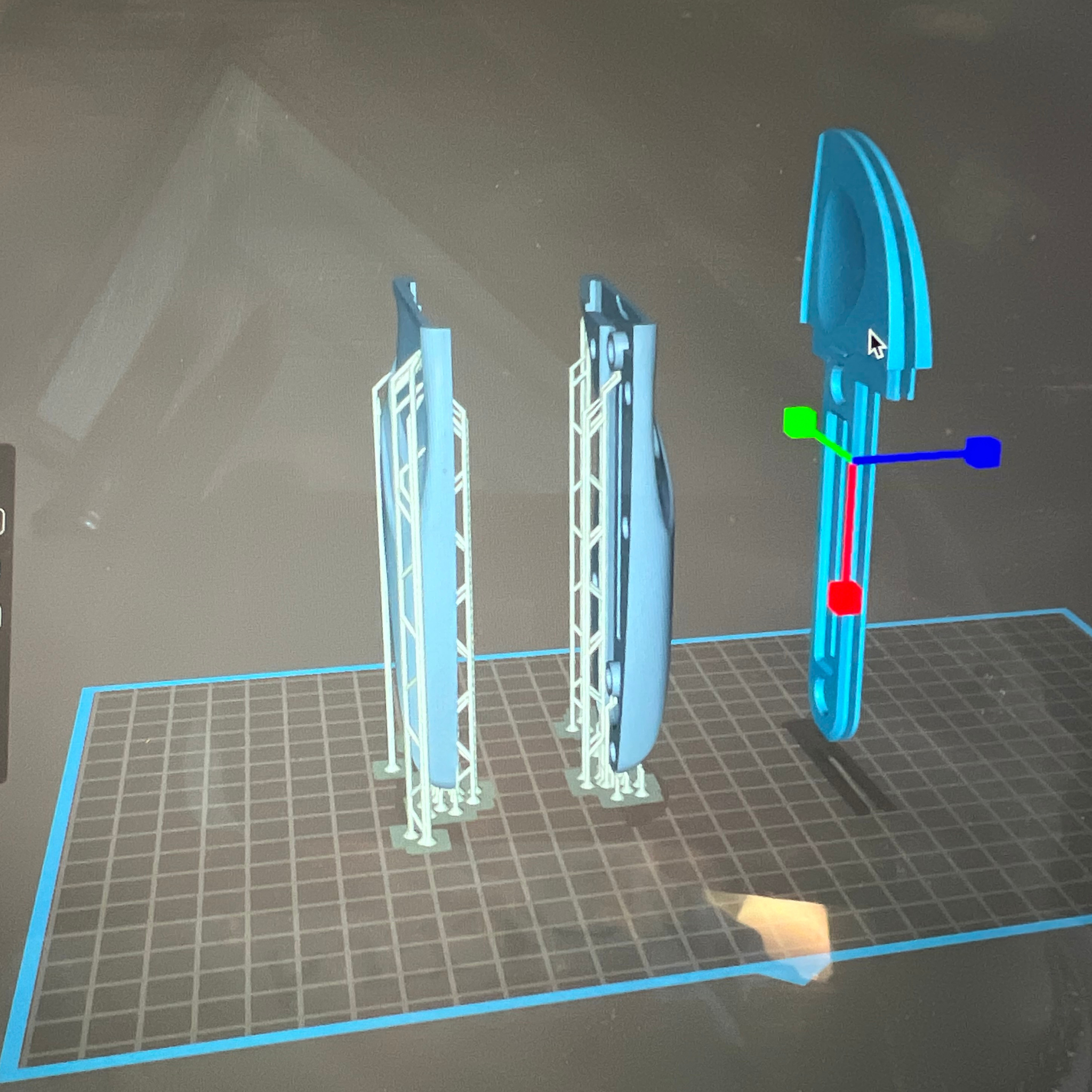 3D model of a blue tool on a grid surface with measurement indicators.