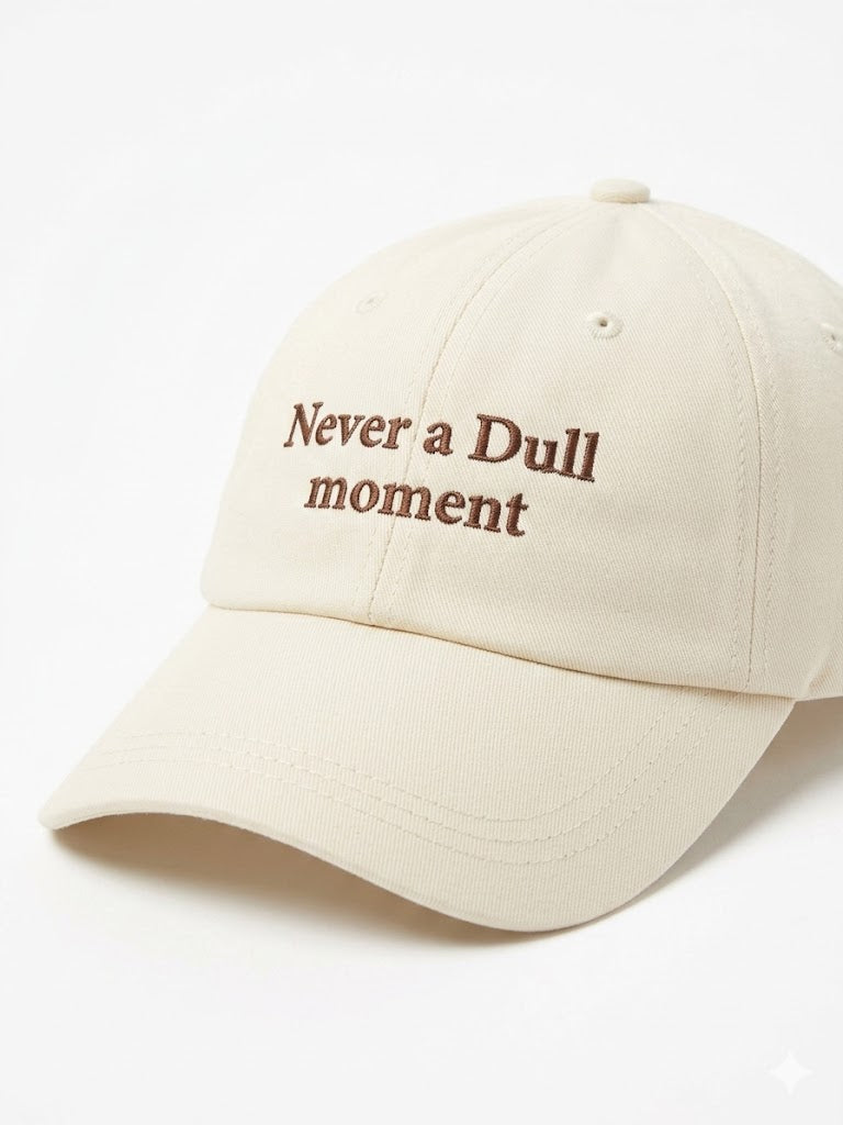 Beige cap with 'Never a Dull Moment' text on a white background