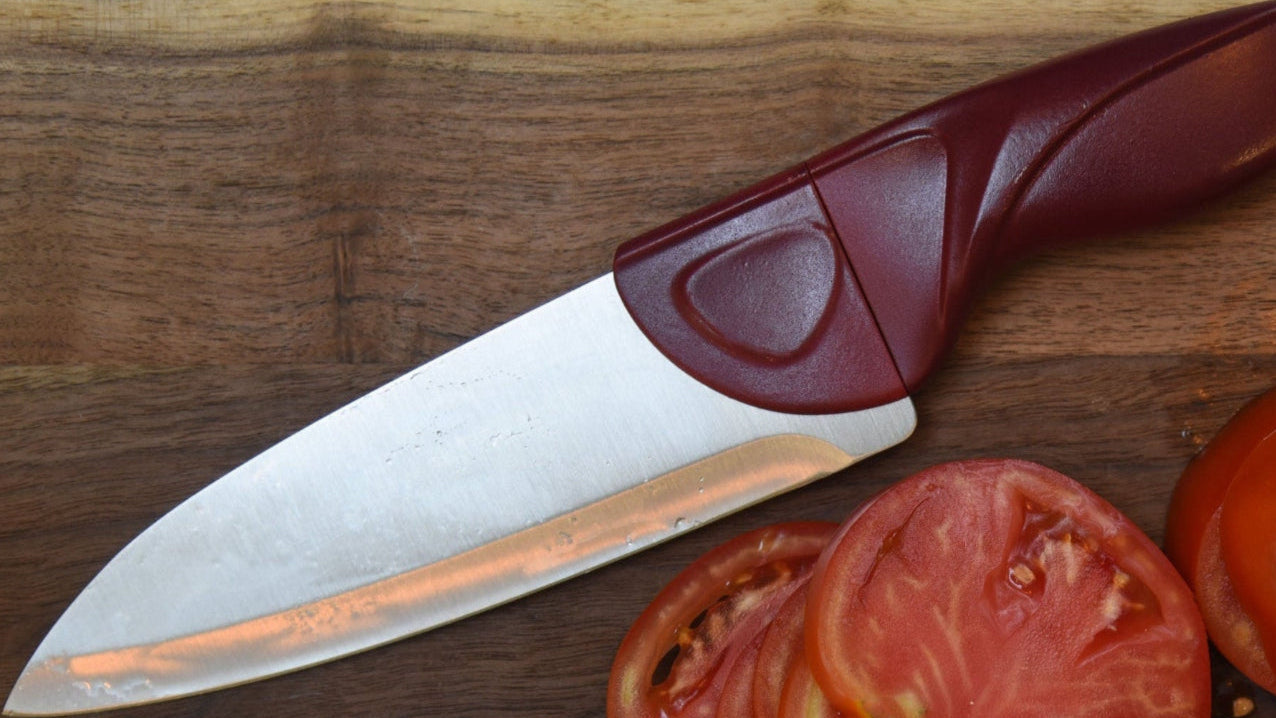 Knife with a brown handle and sliced tomatoes on a wooden surface