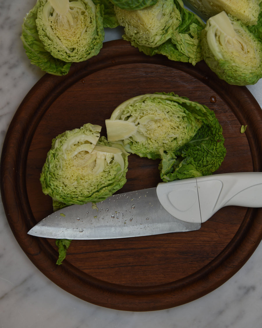 Sliced green cabbage on a wooden cutting board with a knife