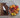 A Grey Chef Knife with a Waffle Striped Navy Kitchen Towel, a Bowl of mixed onion, shallot, tomatoes and citrus, a chef knife for women, on a wood cutting board on a marble countertop