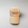 Beige cap with 'Never a Dull Moment' text on a light gray background