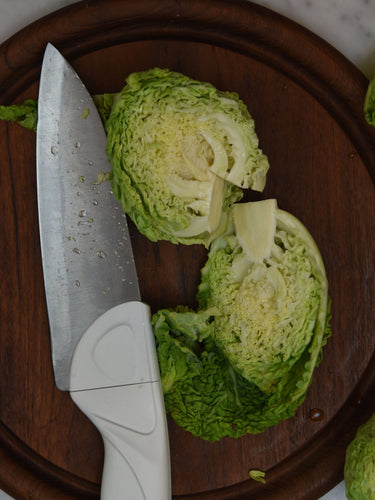 Sliced green cabbage on a wooden cutting board with a knife