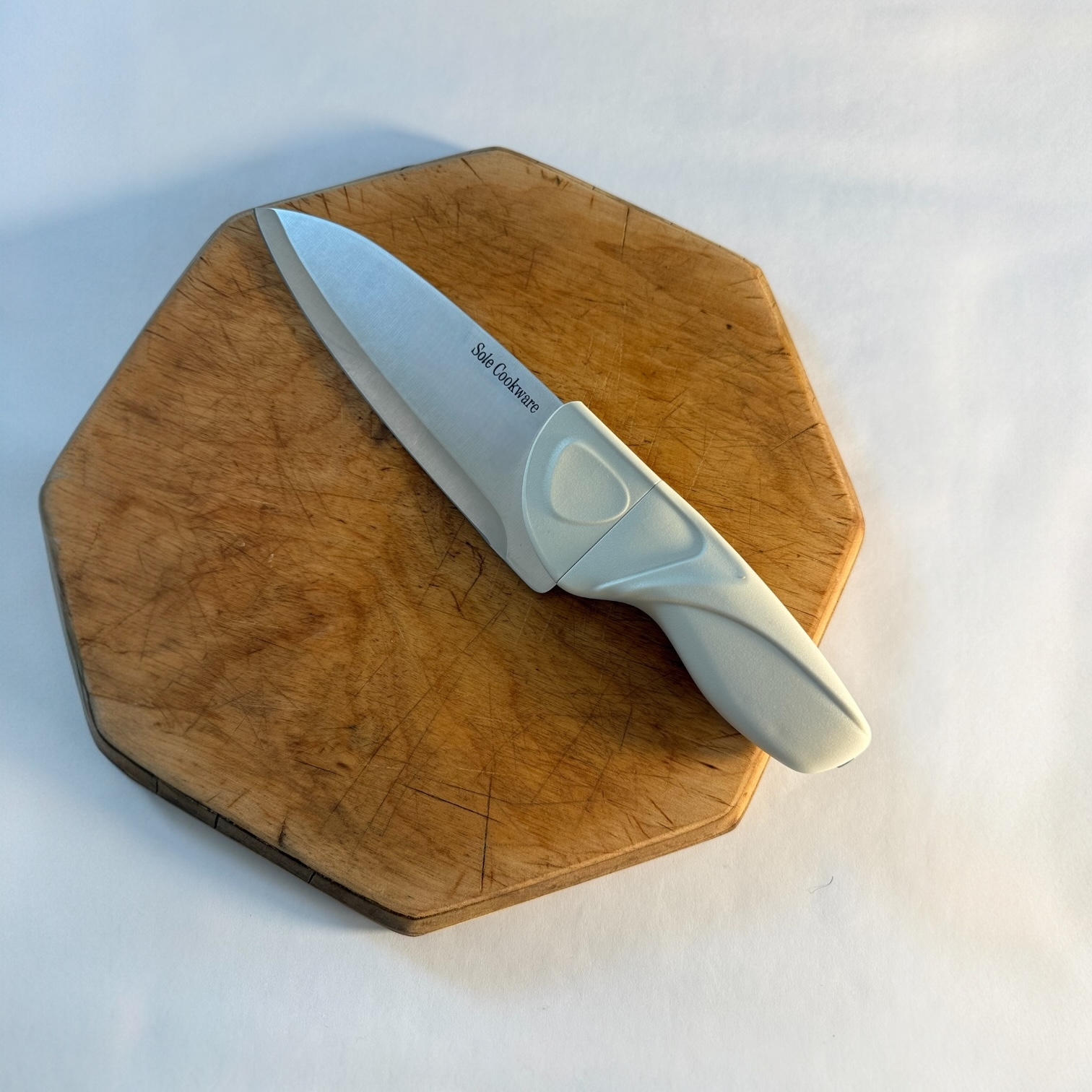 Cream Knife with a white handle on a wooden cutting board against a white background