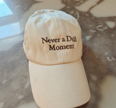 beige canvas baseball hat with brown writing ' never a dull moment' Arabescato brown marble 